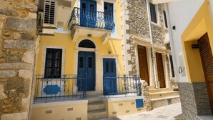 A traditional Mediterranean-style building with stone walls, blue doors, and balconies with wrought iron railings. - Kalymnos Island Gentaway - Chora Central Location (Kalymnos)
