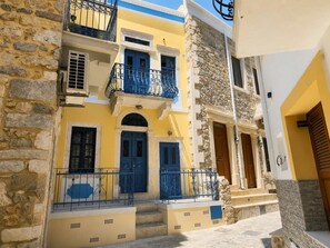 Ein traditionelles Gebäude im mediterranen Stil mit Steinwänden, blauen Türen und Balkonen mit schmiedeeisernen Geländern.