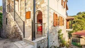 Un bâtiment en pierre avec un escalier, des volets en bois et un balcon.