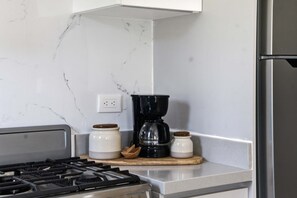 Eine Küche mit einem Gasherd, einer Kaffeemaschine und zwei Gläsern auf einer Arbeitsfläche.