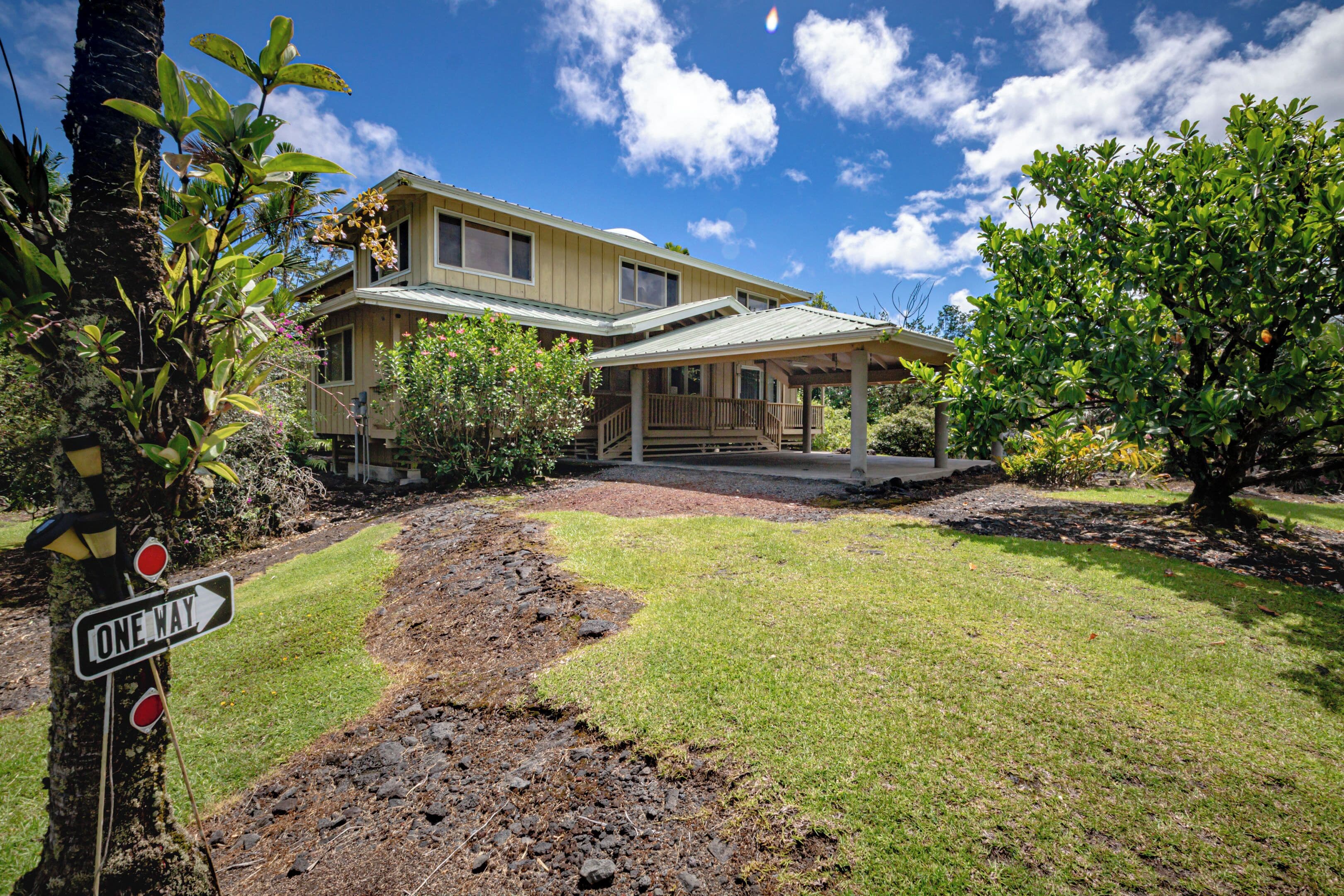 A two-story house with a covered porch and a driveway leading to the entrance.