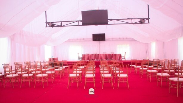 Un espacio para eventos con carpas, filas de sillas y un escenario con un orador.