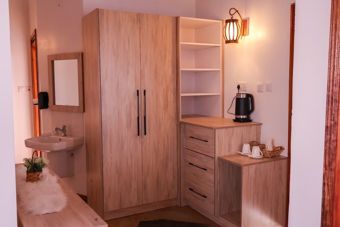 A compact room with a wooden wardrobe, a sink, and a small coffee table.