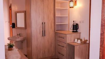 A compact room with a wooden wardrobe, a sink, and a small coffee table.