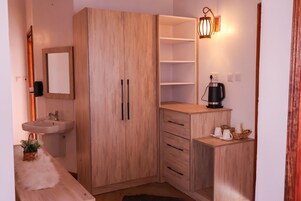 Una habitación pequeña con un armario de madera, un lavamanos y una mesita de café.