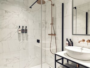 A modern bathroom with a glass-enclosed shower, a white marble floor, and a large mirror. - The ALD Boutique Apartments (Den Haag)