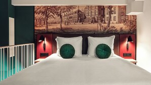 Quarto com uma cama grande, duas almofadas decorativas verdes, cabeceira com luzes fixadas na parede e um mural com vista para a cidade acima da cama.