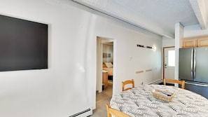 Una cocina moderna con refrigerador integrado, una mesa de comedor con sillas y un pasillo que conduce a un dormitorio.