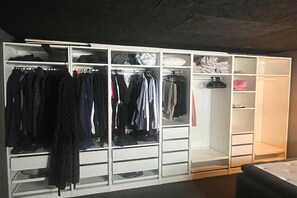 Un dressing avec de nombreuses étagères et tiroirs, contenant divers vêtements et chaussures.