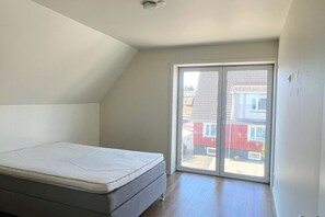 A bedroom with a single bed, a sliding glass door to a balcony, and a sloped ceiling. - Wonderful Penthouse in Frederikshavn (Frederikshavn)