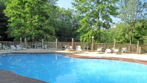Una piscina con cubierta de madera, rodeada de árboles.