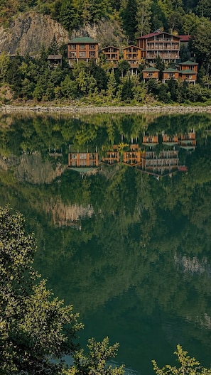 Una propiedad junto al lago con varias edificaciones de madera, algunas con balcones, reflejándose en el agua.