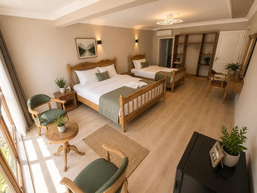 A hotel room with two wooden beds, a sitting area with a chair and a small table, and a wardrobe.