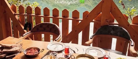 A wooden table set for a meal with a view of a mountainous landscape.