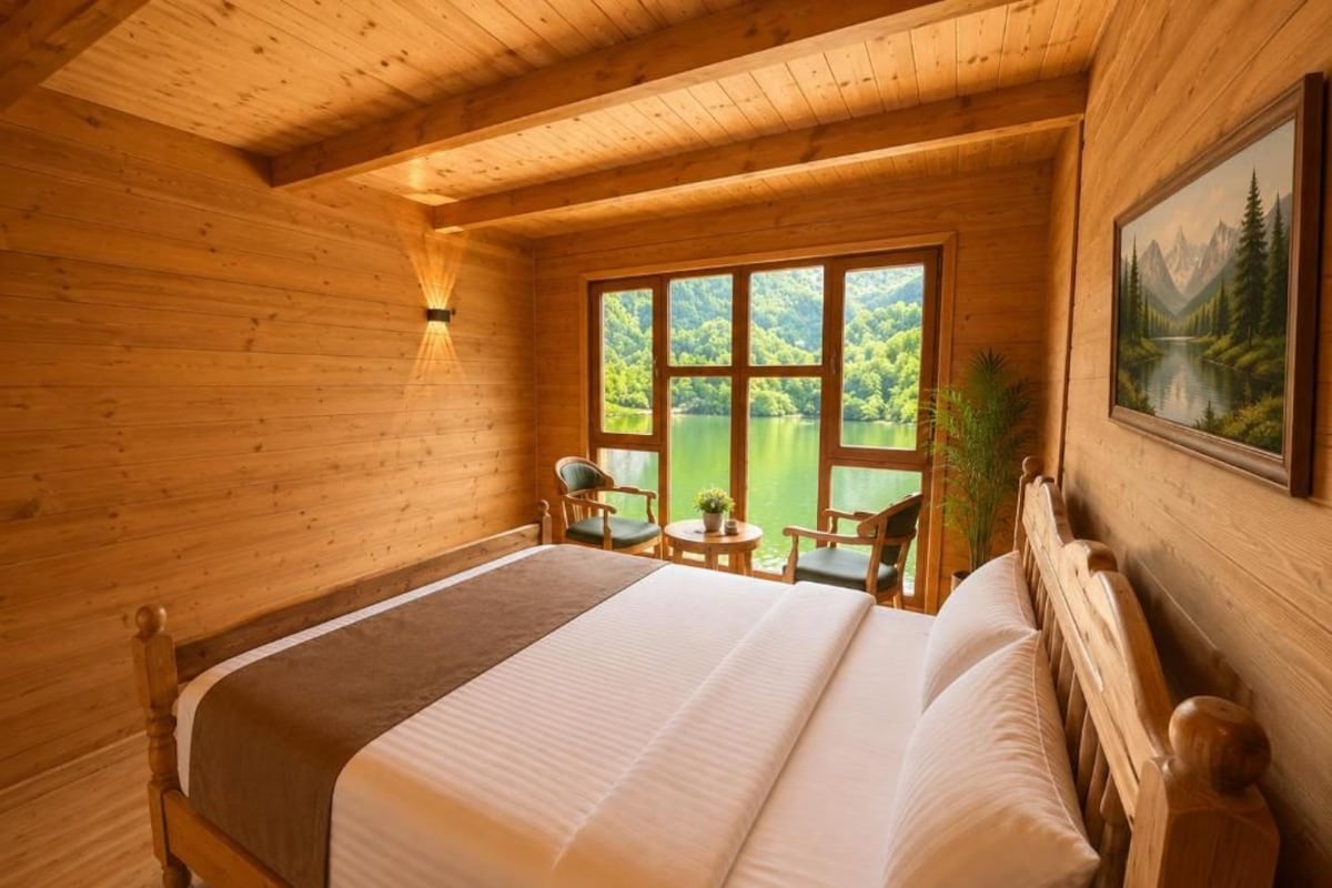 Un dormitorio de cabaña de madera con una cama grande, una ventana con vista a un lago y un cuadro en la pared.