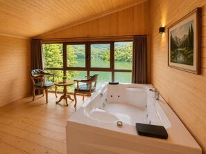 A wooden cabin room with a large window, a hot tub, and a dining area. - Buneba Resort (Borçka)