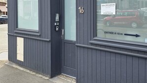 A building with a dark facade, a large window with signage for 'ARRAS PÔLE PARAMÉDICAL', and a door with the number 16. - T2 l Gant Devant la Mairie - Calme - Centre (Arras)