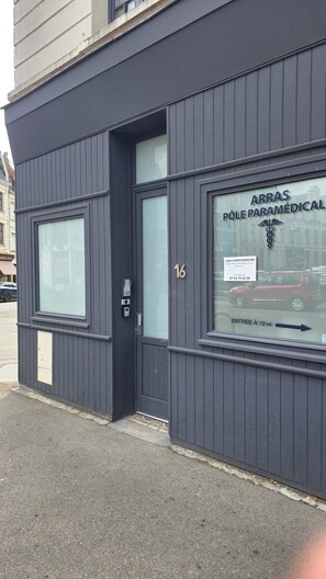 Ein Gebäude mit dunkler Fassade, ein großes Fenster mit der Beschriftung 'ARRAS PÔLE PARAMÉDICAL' und eine Tür mit der Nummer 16.