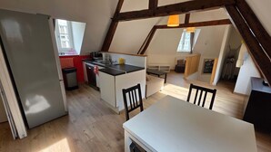 A compact kitchen with a refrigerator, sink, and wooden dining table. - T2 l Gant Devant la Mairie - Calme - Centre (Arras)