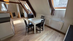 Un coin repas avec une table et des chaises, un radiateur et une fenêtre avec des rideaux.