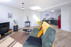 Una sala de estar moderna con un sofá, televisor y un comedor con mesa y sillas.