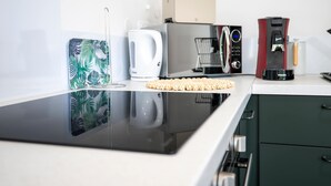 Eine moderne Küche mit schwarzem Arbeitsplatz, einer Kaffeemaschine, einer Mikrowelle und einem Wasserkocher.