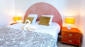Ein ordentlich bezogenes Bett mit einer Zebradecke, zwei Kissen, einem Handtuch und zwei Nachttischlampen.