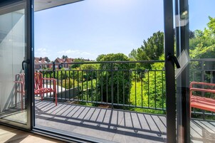 Un balcón con vistas a un jardín verde y casas.