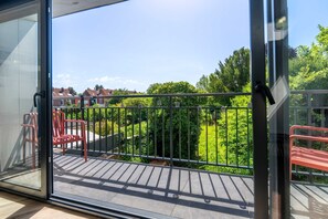 Un balcón con vistas a un jardín verde y casas.
