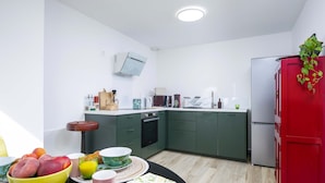 Eine moderne Küche mit grünen Schränken, einem roten Kühlschrank und einem Essbereich mit Frühstücksangeboten.