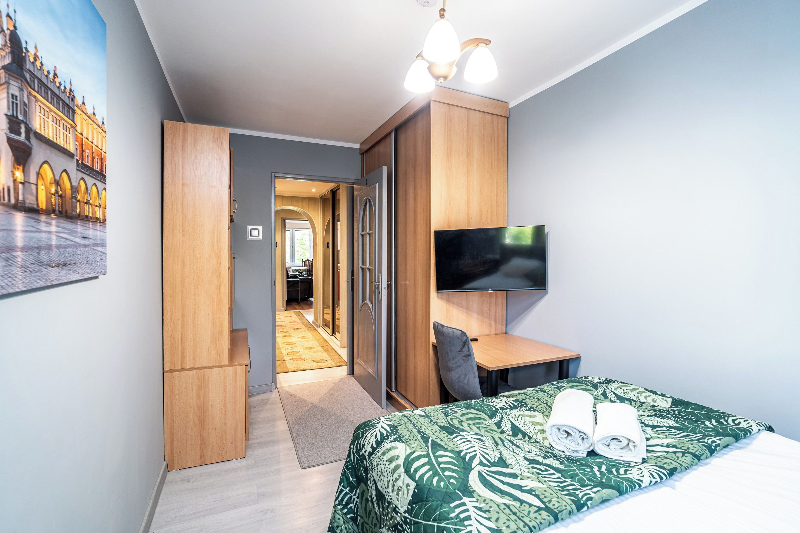 A hotel room with a bed, a TV, a desk, and a wardrobe.