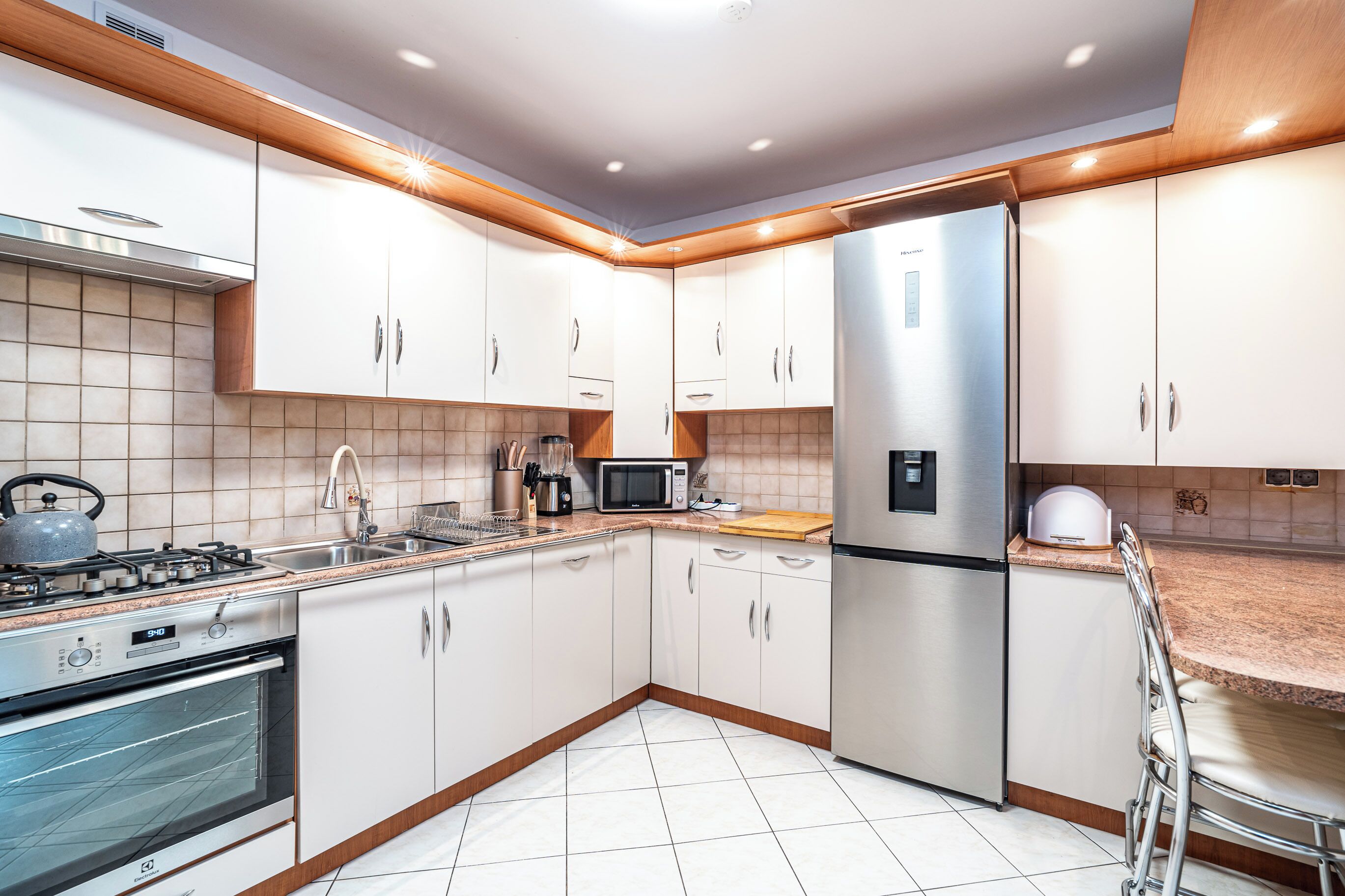 A modern kitchen with stainless steel appliances, white cabinetry, and a tiled backsplash.