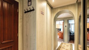 A hotel hallway with a wooden door, a coat rack, and a 'No Smoking' sign. - RentPlanet - Apartament Weissa (Kraków)