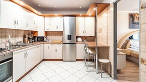 A modern kitchen with stainless steel appliances, white cabinetry, and a tiled floor. - RentPlanet - Apartament Weissa (Kraków)