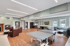 Ein geräumiger Raum mit Tischtennisplatte, Sitzecke und Fernseher.