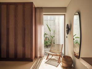 Une pièce comprenant une armoire en bois, une chaise en osier, un panier tressé et un grand miroir accroché au mur.