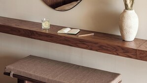 Une salle de bain avec un meuble-lavabo en bois, un miroir rond, un évier et un vase contenant des plantes séchées.
