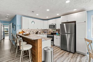 Eine moderne Küche mit weißen Schränken, Edelstahlgeräten und einer Holz-Kochinsel mit Barhocker.