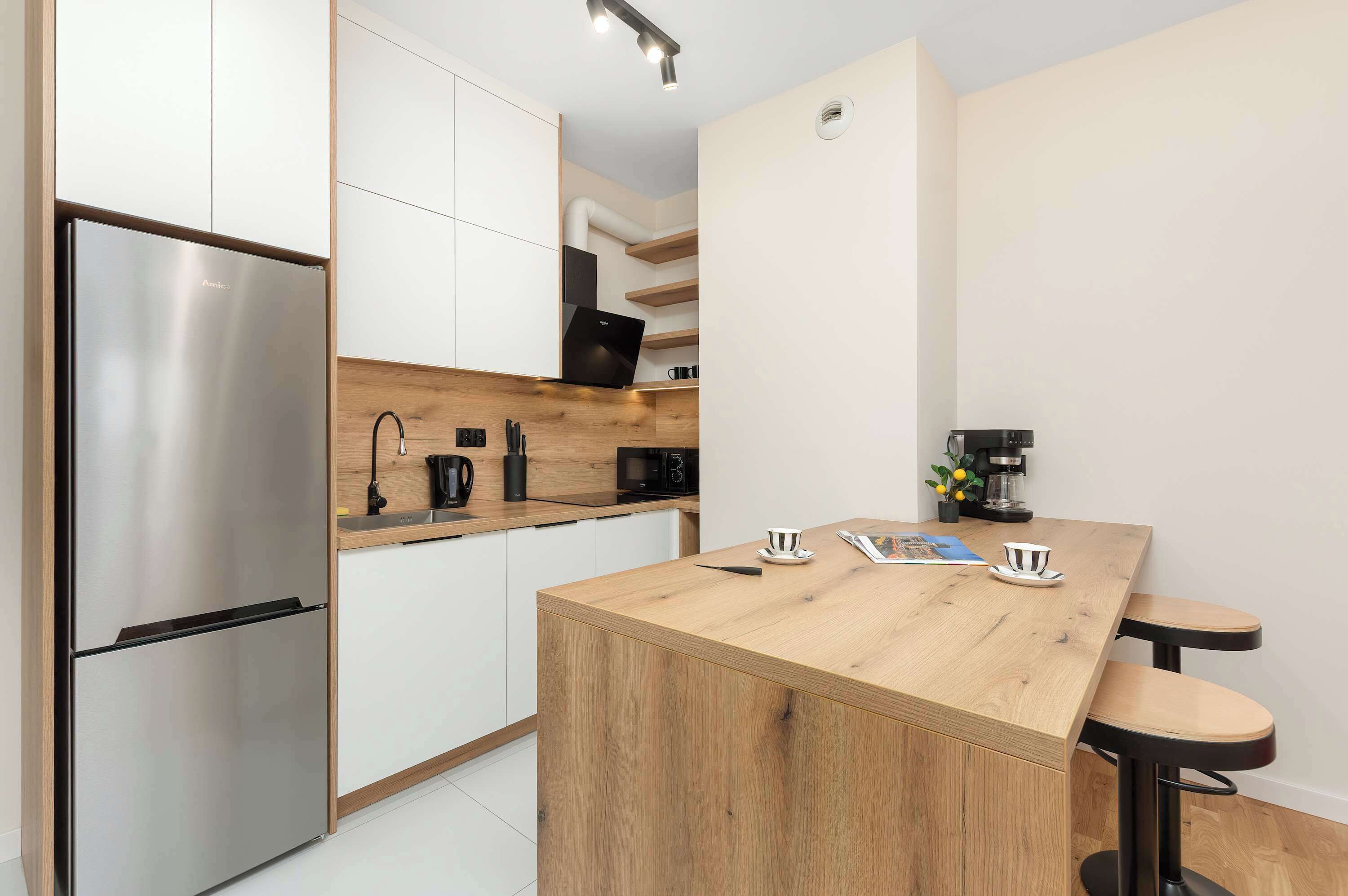 Una cocina moderna con refrigerador de acero inoxidable, encimera de madera y una cafetera.