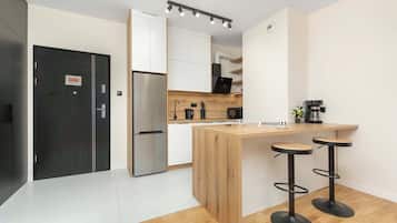 Eine moderne Küche mit einem eingebauten Kühlschrank, einer Kaffeemaschine und einer Holzeile mit Barhocker.