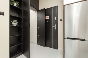 Uma cozinha moderna com frigorífico de aço inoxidável, armários pretos e chão de azulejos brancos.