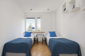 A bedroom with two beds, a window, a radiator, and a small table with a lamp. - Practical Family Apartment | 2 Bedrooms | Close to the Airport (Warszawa)