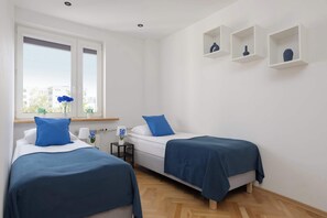Ein Schlafzimmer mit zwei Betten, einem Fenster mit Ausblick und einem kleinen Tisch mit Lampe.