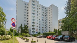 A multi-story residential building with a parking area in front. - Practical Family Apartment | 2 Bedrooms | Close to the Airport (Warszawa)