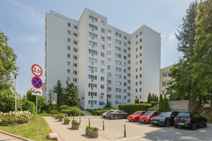 A multi-story residential building with a parking area in front. - Practical Family Apartment | 2 Bedrooms | Close to the Airport (Warszawa)