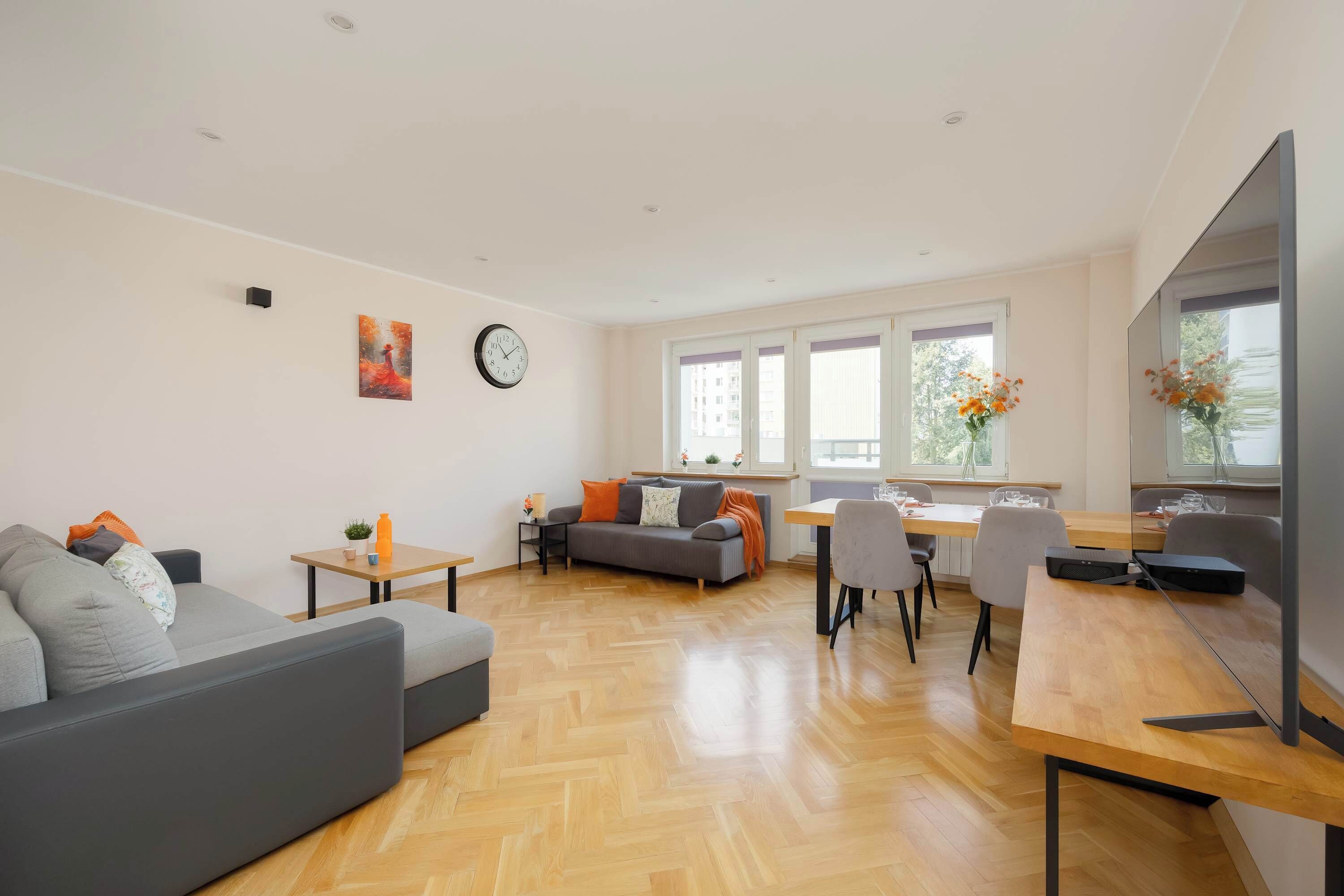Uma sala de estar moderna com sofá, mesa de jantar e televisão.