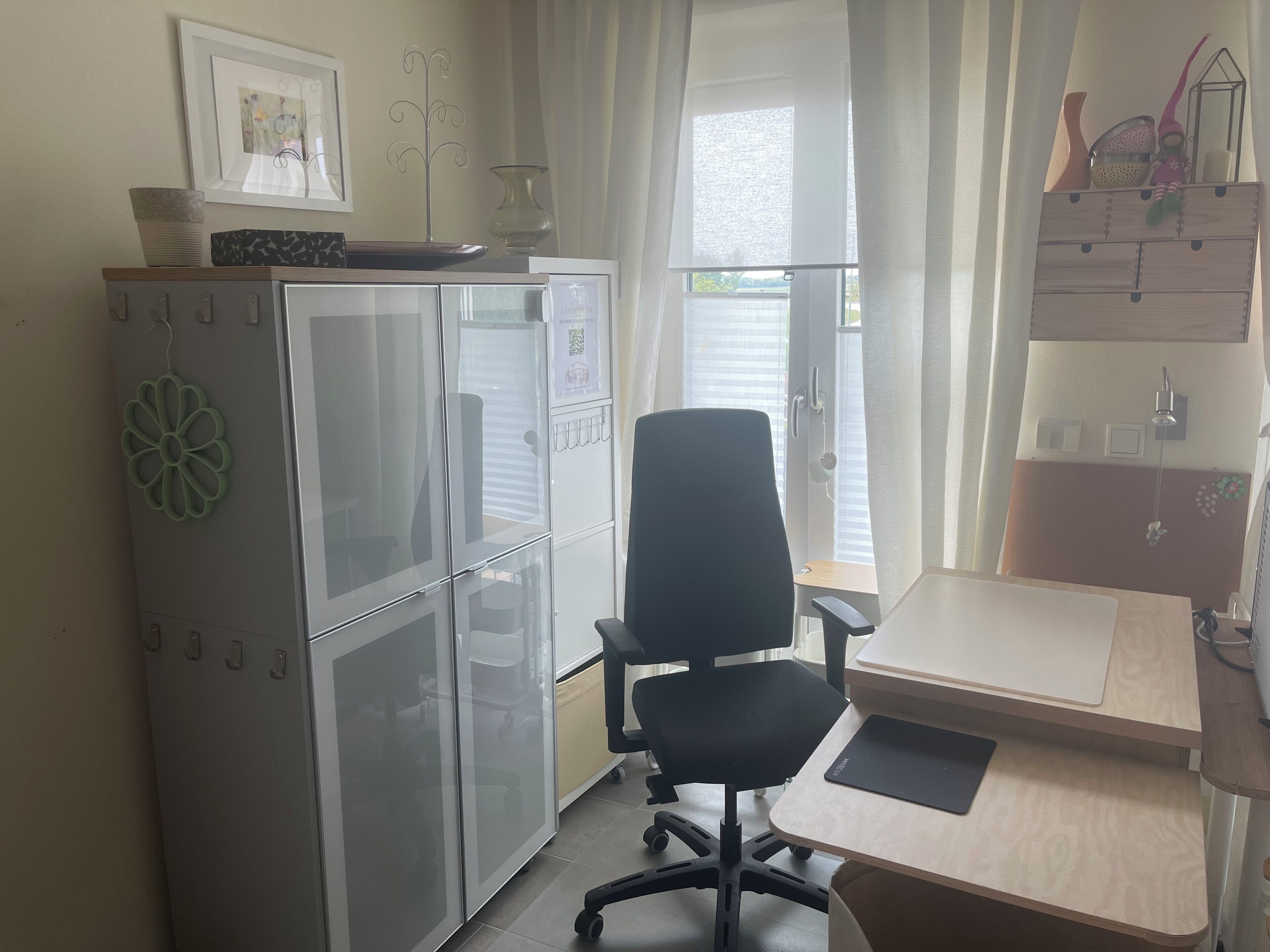 Un espacio de oficina pequeño con un escritorio, una silla y un armario con puerta de vidrio.