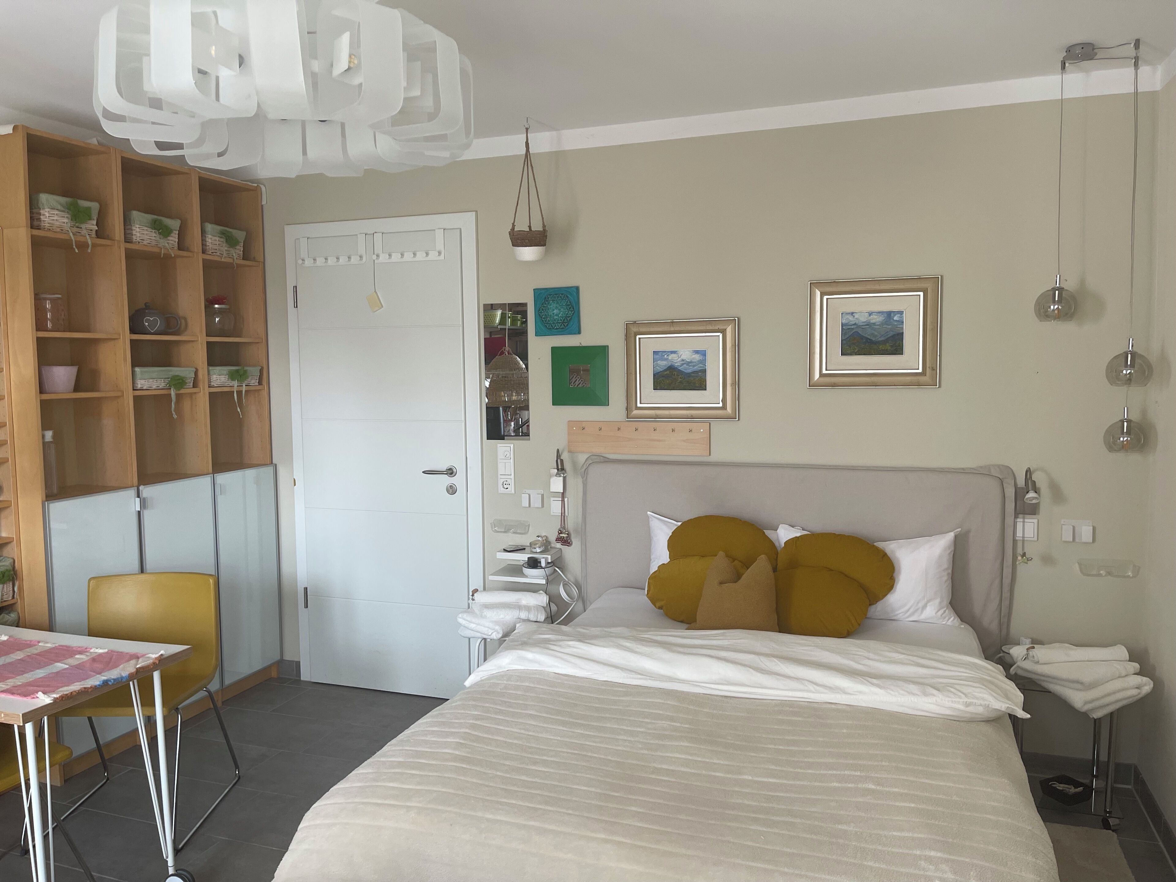 Ein Hotelzimmer mit Bett, Schreibtisch, Stuhl, Kleiderschrank und einer Pendelleuchte.