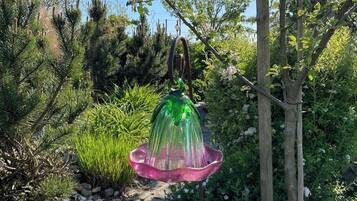 Un jardín con un bebedero para pájaros, plantas diversas y una cerca de madera.