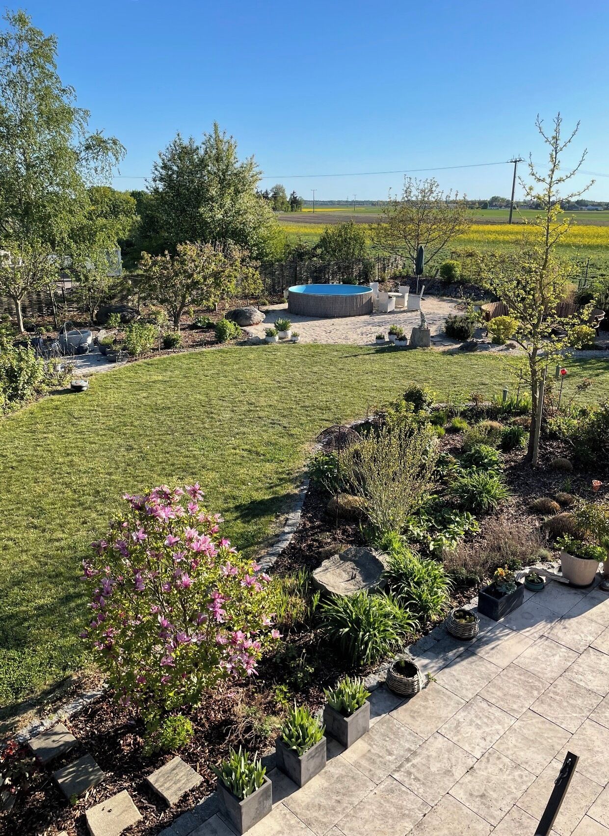 Un jardín ajardinado con piscina, mobiliario exterior y una gran variedad de plantas.